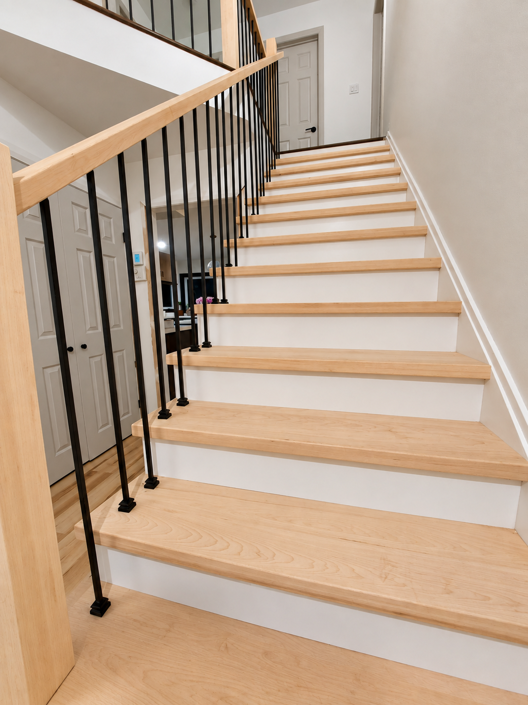 Fineline staircase with pale wood treads, white risers and black metal balusters